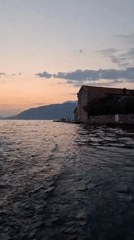 Feet in the water, stone building, calm day in Montenegro