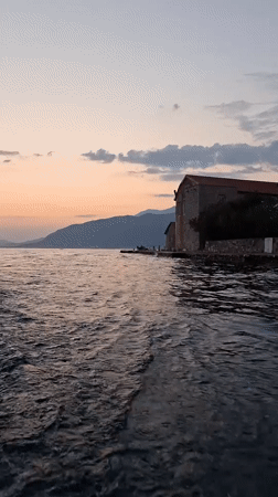 Feet in the water, stone building, calm day in Montenegro