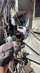 Crowds move through rubble-filled Gaza alleyways amid heavy building damage