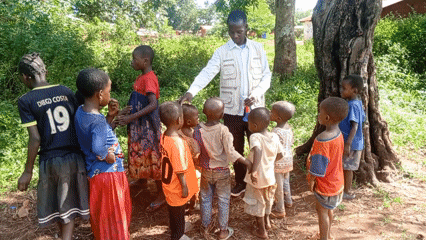 Adult teaches group of children in rural Congo village