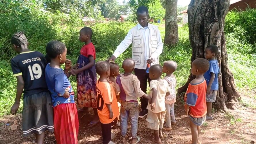 Adult teaches group of children in rural Congo village
