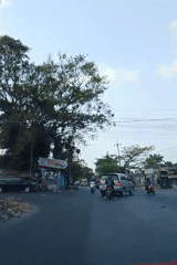 Morning traffic and street vendors along a busy Malang road