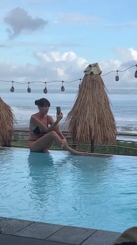 Woman photographs resort pool scene in Mengwi, Indonesia