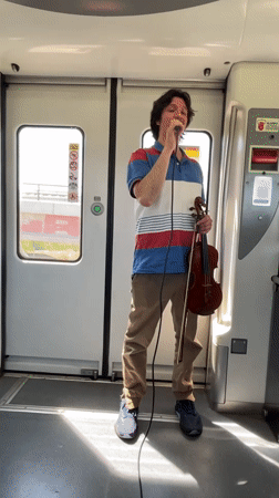 Street musician performs with violin at Spanish train station