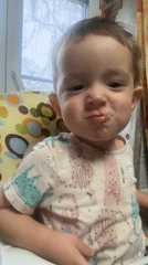Child in cartoon cat shirt sits in colorful high chair