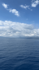 Calm ocean waters filmed with distant coastline visible