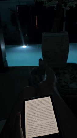 Person reads Russian text on tablet by pool in Kuta