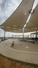 Scooter riders use shaded concrete bowl at Tel Aviv skate park