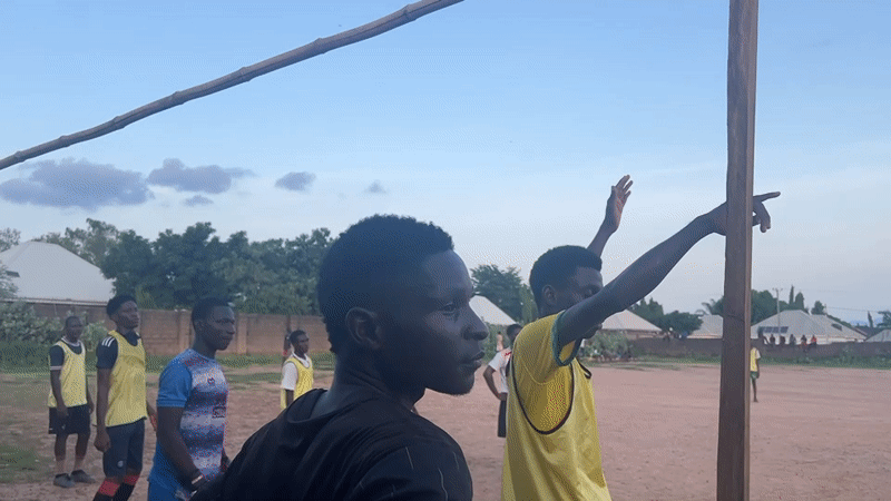 Young men play soccer on dirt field in Jalingo