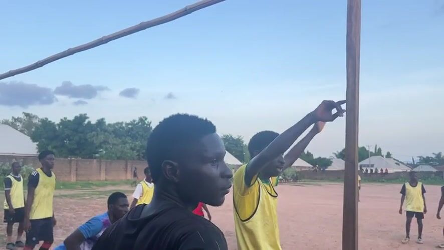Young men play soccer on dirt field in Jalingo
