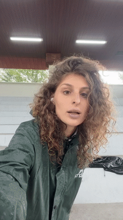 Woman in raincoat visits soccer facility during rain in Indonesia