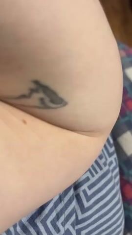 The video shows a close-up view of a person's arm with several tattoos. The tattoos include a black outline of a creature, possibly an animal with pointed ears and an open mouth, and a smaller, simpler drawing of a figure with a round head and a body, appearing to be upside down. Further up the arm, Roman numerals "IX" are tattooed in bold black ink, with a hint of red visible around them. The arm is resting on a surface covered with a plaid blanket in shades of blue, purple, and white, with another plaid pattern visible in the background. The lighting suggests an indoor setting. There is no discernible activity taking place; the focus is on the tattoos and the arm itself. No time of day or weather conditions can be determined. No specific emotional expressions are visible. The location context provided is Muravlenko, Russia.
