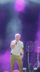 Live concert: gray-haired vocalist performs on a lit stage