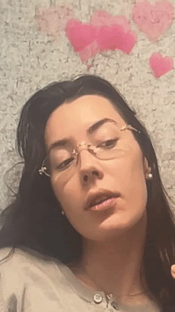 Woman makes shushing gesture while multitasking on laptop in Dubai