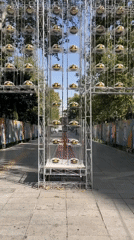 Cross-shaped metal structure displays rows of white and gold caps