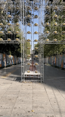 Cross-shaped metal structure displays rows of white and gold caps