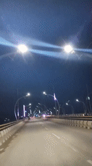 Nighttime drive across a lit bridge in Meureudu, Indonesia
