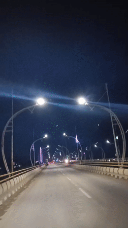 Nighttime drive across a lit bridge in Meureudu, Indonesia