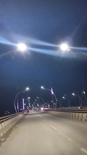 Nighttime drive across a lit bridge in Meureudu, Indonesia