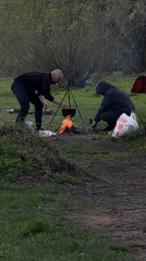 Two men cook over campfire in Moscow park