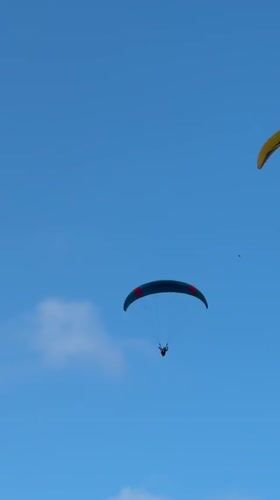 Paragliders and a helicopter share the skies over Kuta Selatan