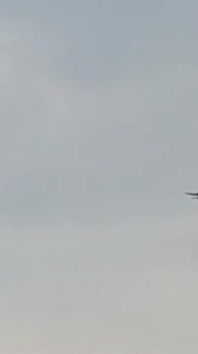 Parachutists descend over a quiet Bulgarian village on a grey morning