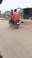 Man carries two bicycles on moped in Nigeria