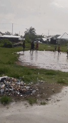Young men play soccer in flooded field in Nigeria
