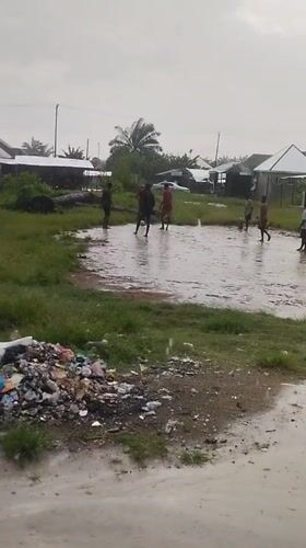 Young men play soccer in flooded field in Nigeria