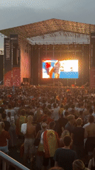 Crowd gathers outdoors to watch soccer match on giant screen