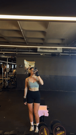 Woman films workout selfie in Bat Yam gym mirror