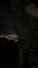 Two people observe illuminated city from nighttime viewpoint in Montenegro