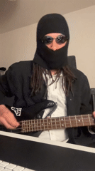 Masked musician plays bass guitar in London street performance