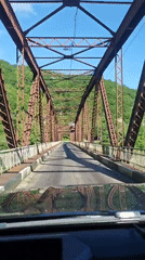 Vehicle crosses old metal truss bridge in Abkhazia
