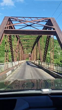 Vehicle crosses old metal truss bridge in Abkhazia
