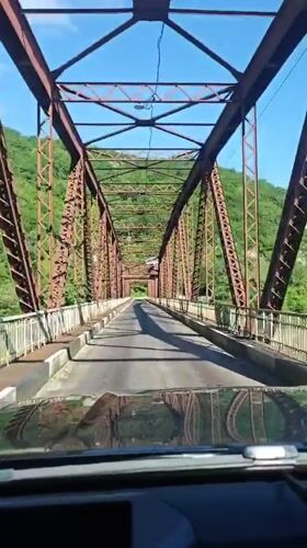 Vehicle crosses old metal truss bridge in Abkhazia