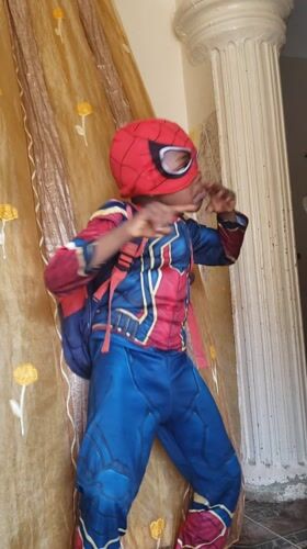 Child plays in Spider-Man costume on bed in Nigeria