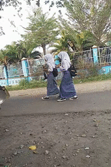 School-morning street life around a food cart in Begajah