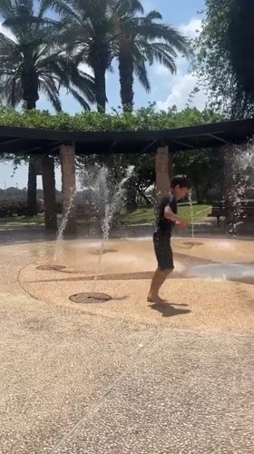 Young person plays barefoot in Haifa water park fountains