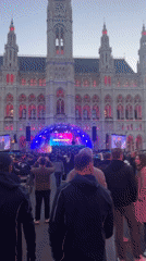 Crowd gathers at pink-lit Vienna building with stage setup
