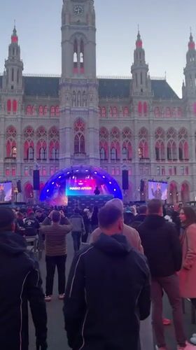 Crowd gathers at pink-lit Vienna building with stage setup