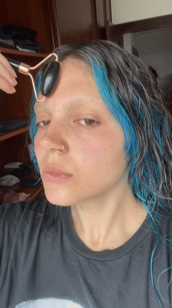 Woman performs facial roller skincare routine in Gijón, Spain