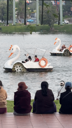 Visitors gather at Da Lat lake watching boats, paddle boats