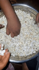 Multiple hands share popcorn from bowl in Onitsha