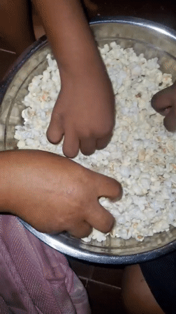 Multiple hands share popcorn from bowl in Onitsha