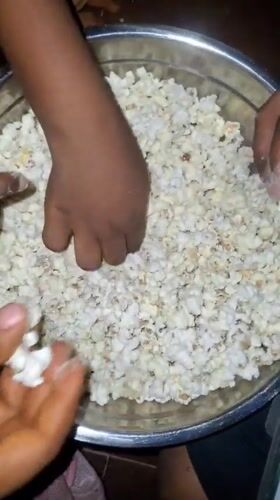 Multiple hands share popcorn from bowl in Onitsha