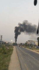 Black smoke rises from trucks in Kohalpur street scene