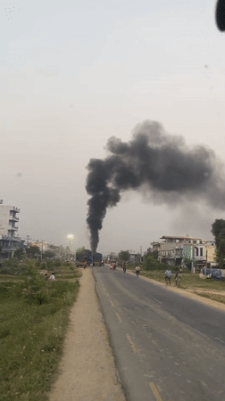 Black smoke rises from trucks in Kohalpur street scene