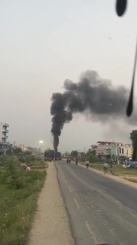 Black smoke rises from trucks in Kohalpur street scene