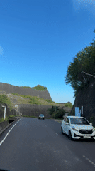 Traffic flows through rock-walled road in Kuta Selatan